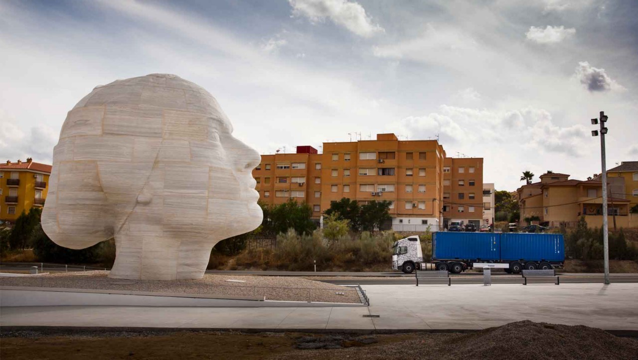 Ein Testfahrzeug fährt in Spanien an einer Marmorstatue vorbei